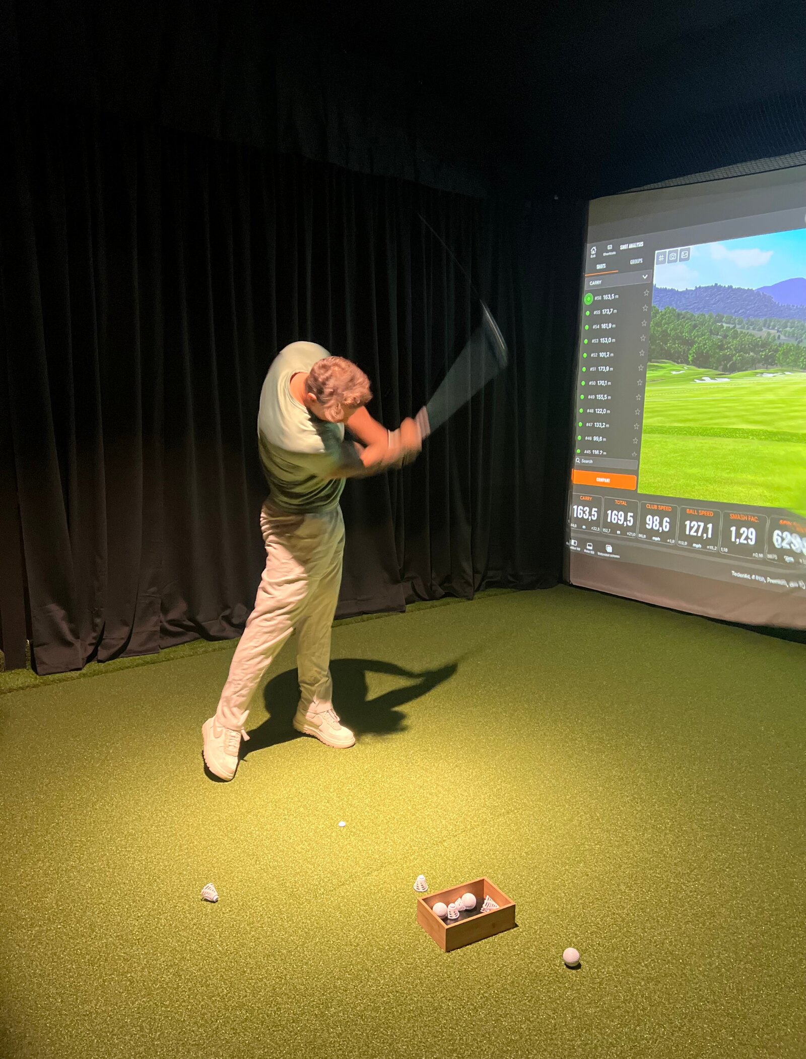 Spelare mitt i sving framför TrackMan-skärm